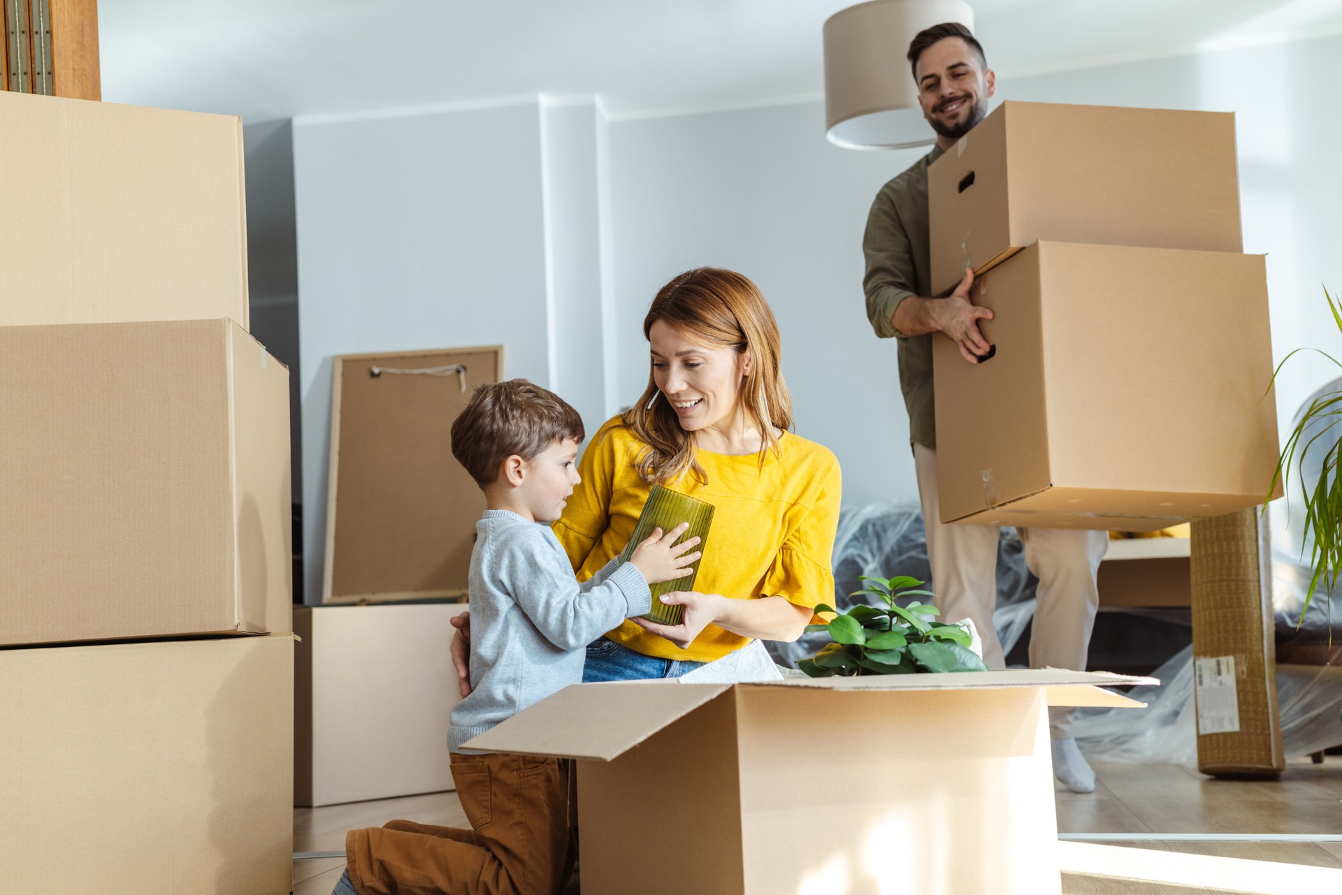 Happy young family unpacking belongings from boxes in new apartment