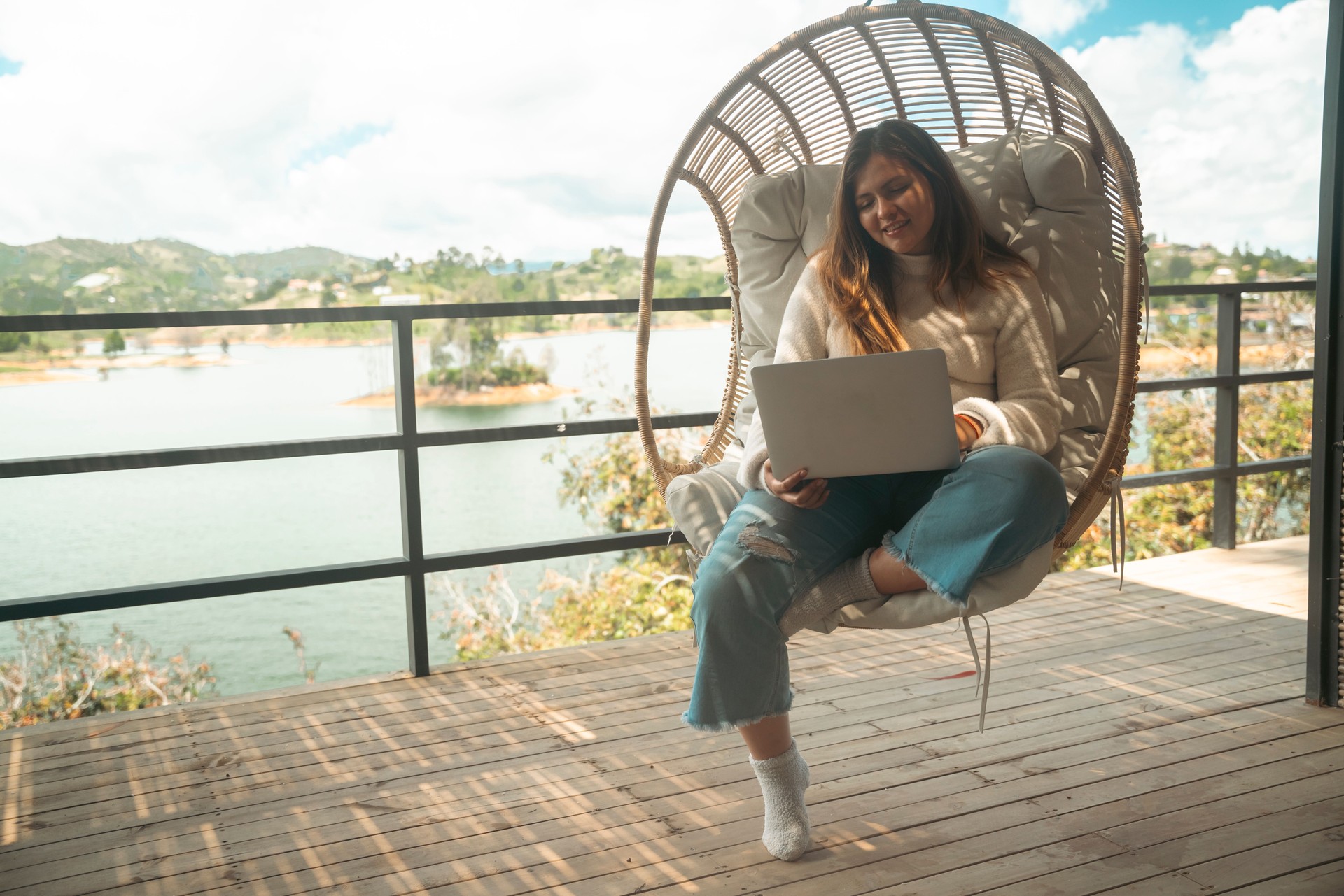 Young woman working on the balcony on her computer with a great view, living the nomadic lifestyle